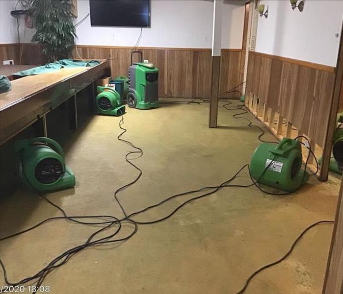 Basement club room with carpet removed, and green servpro fans drying out the room
